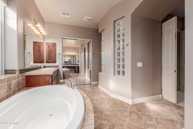 bathroom featuring tiled bath, vanity, and tile patterned floors