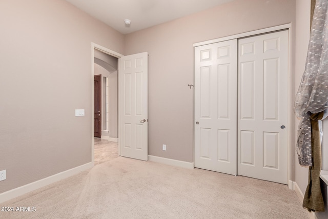 unfurnished bedroom featuring light carpet and a closet