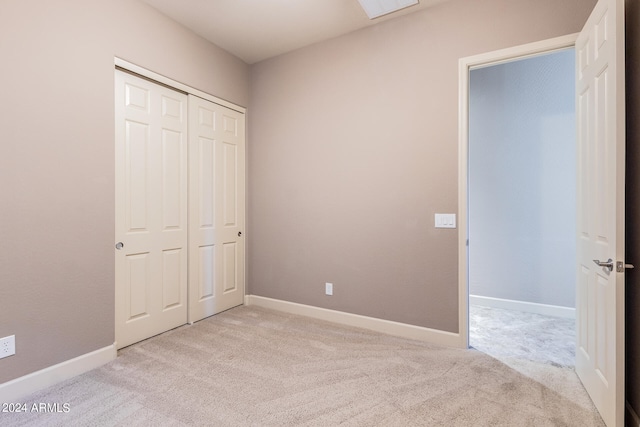 unfurnished bedroom with light colored carpet and a closet