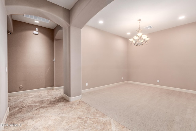 carpeted empty room featuring an inviting chandelier