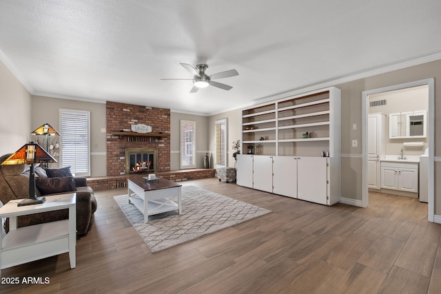 living area with visible vents, crown molding, and wood finished floors