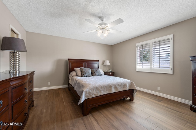 bedroom featuring dark wood finished floors, a textured ceiling, baseboards, and ceiling fan