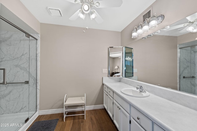 bathroom with a marble finish shower, ceiling fan, vanity, wood finished floors, and baseboards