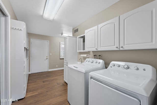 laundry area featuring dark wood-style flooring, visible vents, baseboards, independent washer and dryer, and cabinet space