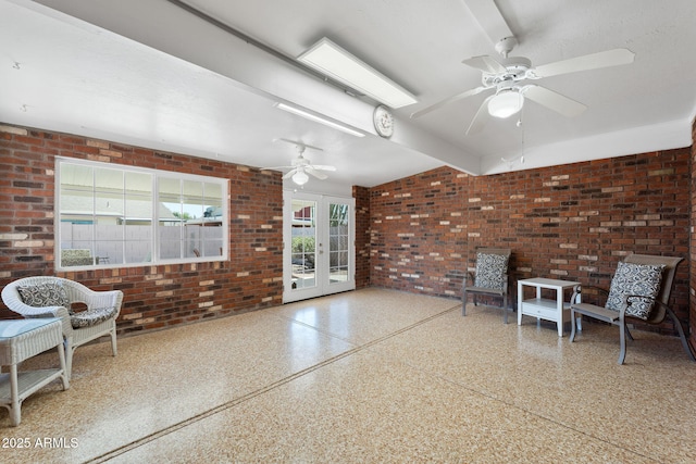 living area featuring french doors, speckled floor, and brick wall