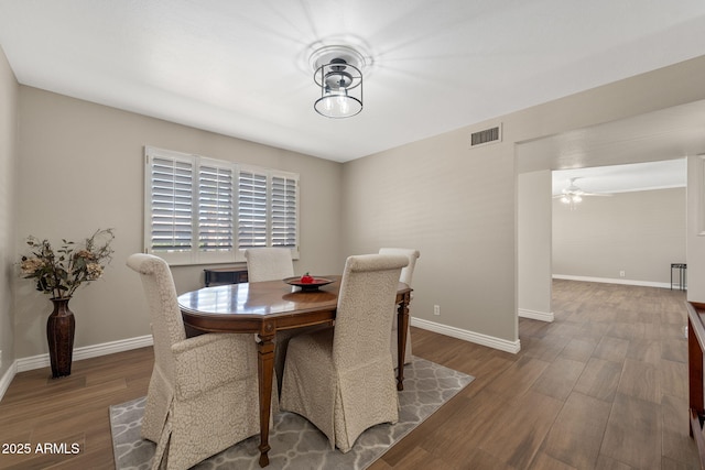 dining space featuring baseboards, visible vents, ceiling fan, and wood finished floors