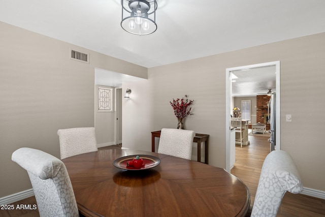 dining room with baseboards, visible vents, ceiling fan, wood finished floors, and a healthy amount of sunlight