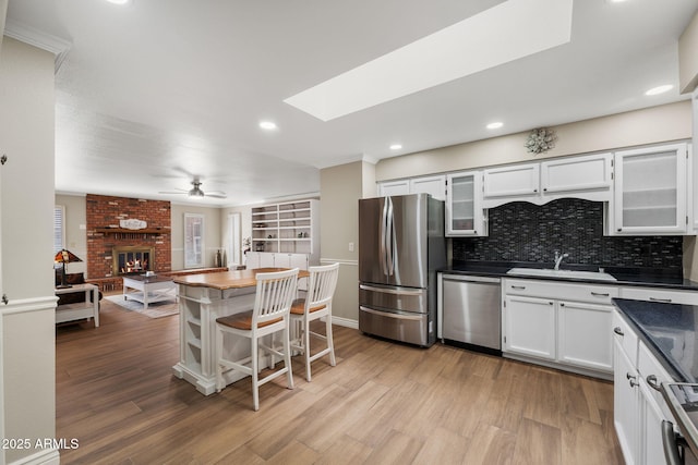 kitchen featuring stainless steel appliances, light wood-type flooring, a sink, and dark countertops