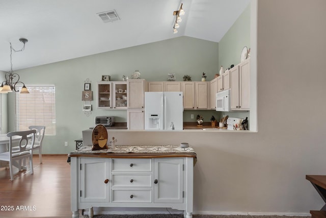 kitchen featuring vaulted ceiling, a chandelier, hanging light fixtures, light hardwood / wood-style floors, and white appliances