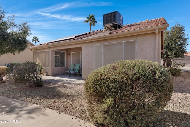 back of property featuring central AC unit, a patio, and solar panels