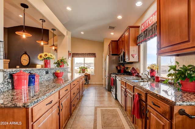 kitchen featuring sink, dark stone counters, decorative light fixtures, lofted ceiling, and appliances with stainless steel finishes