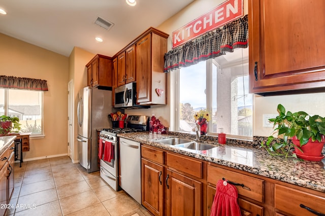 kitchen with stone counters, light tile patterned floors, a healthy amount of sunlight, and appliances with stainless steel finishes