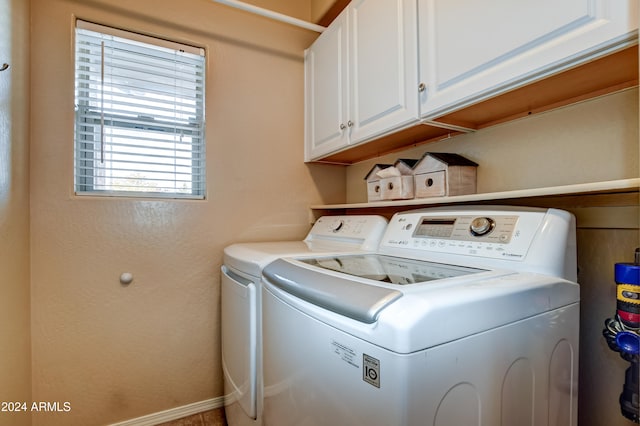 clothes washing area featuring cabinets and washing machine and clothes dryer