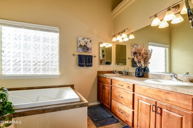 bathroom with tile patterned flooring, vanity, and tiled bath