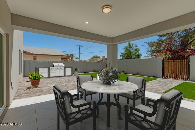 view of patio / terrace featuring outdoor dining area, a fenced backyard, a grill, and an outdoor kitchen