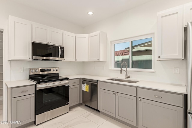 kitchen with appliances with stainless steel finishes, a sink, gray cabinets, marble finish floor, and recessed lighting