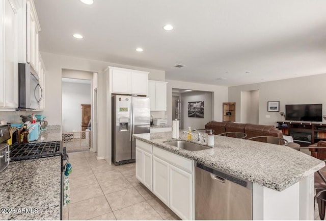 kitchen with white cabinets, stainless steel appliances, a sink, open floor plan, and recessed lighting