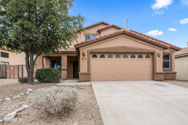 mediterranean / spanish home with driveway, a tile roof, fence, and stucco siding