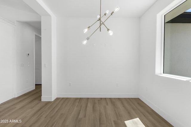 2689 S 305th Ave, Buckeye, AZ 85326 - unfurnished dining area with a chandelier, wood finished floors, and baseboards