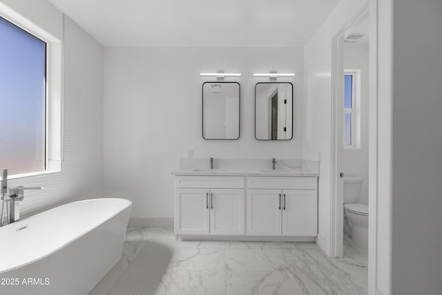 2689 S 305th Ave, Buckeye, AZ 85326 - full bath featuring marble look tiles, toilet, a freestanding tub, double vanity, and baseboards