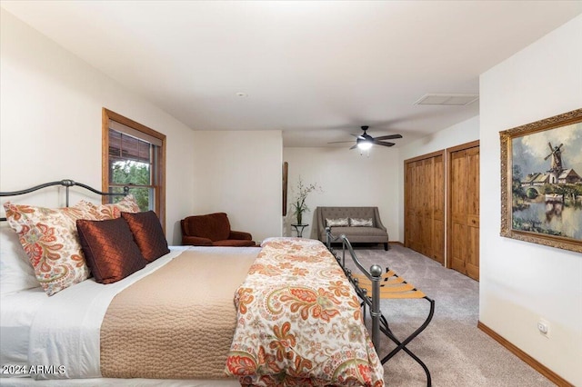 bedroom with ceiling fan, two closets, and light carpet