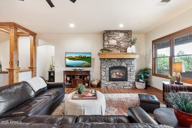 living room with a stone fireplace and wood-type flooring