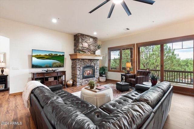 living room featuring hardwood / wood-style floors, a stone fireplace, and ceiling fan