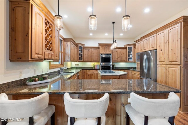 kitchen with light hardwood / wood-style flooring, dark stone counters, a center island, stainless steel appliances, and sink