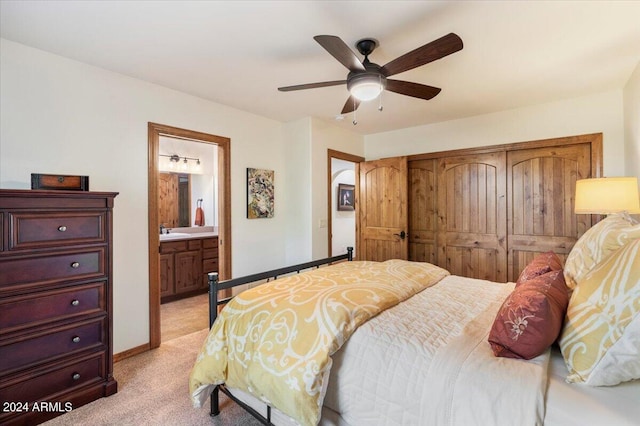 bedroom with ensuite bathroom, a closet, ceiling fan, sink, and light colored carpet