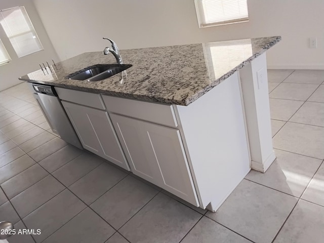 kitchen featuring light stone countertops, an island with sink, white cabinets, and sink