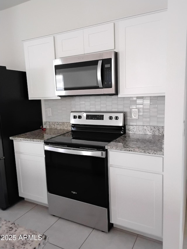 kitchen featuring white cabinets, light tile patterned floors, appliances with stainless steel finishes, and tasteful backsplash