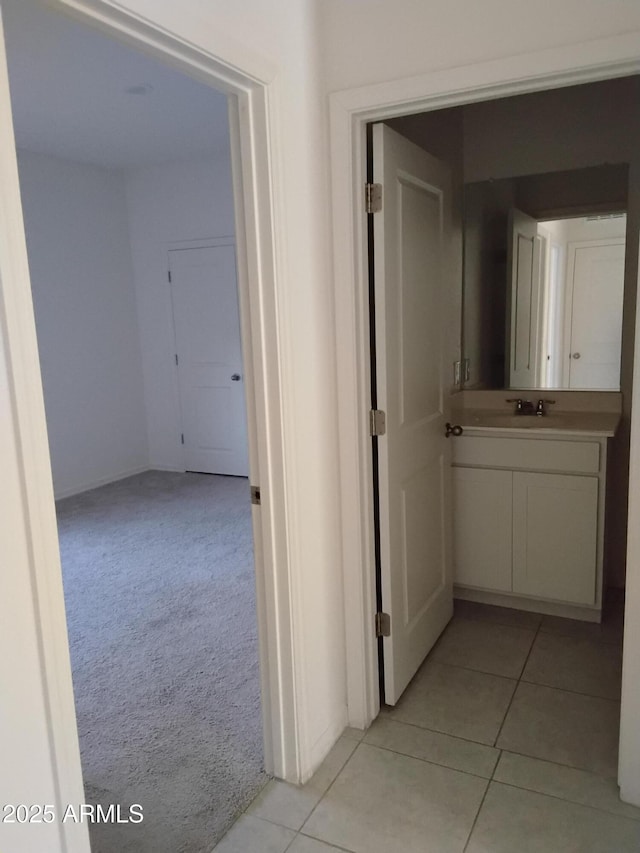 hall featuring sink and light colored carpet