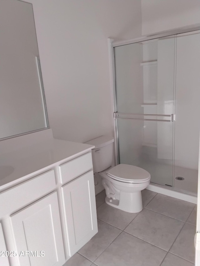 bathroom featuring tile patterned floors, vanity, toilet, and a shower with door