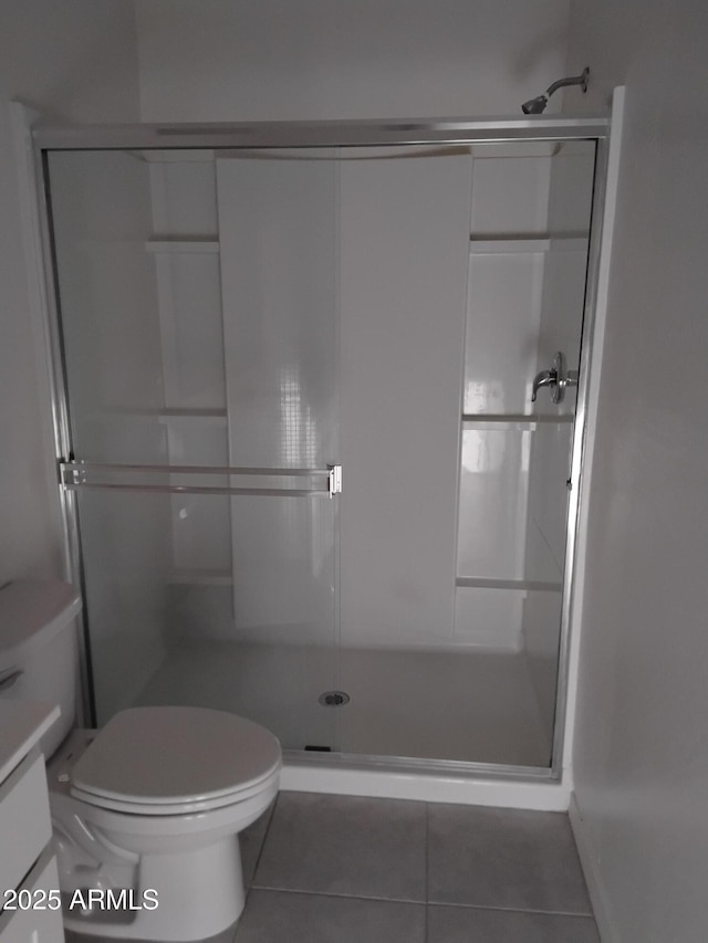 bathroom with tile patterned flooring, vanity, toilet, and a shower with door