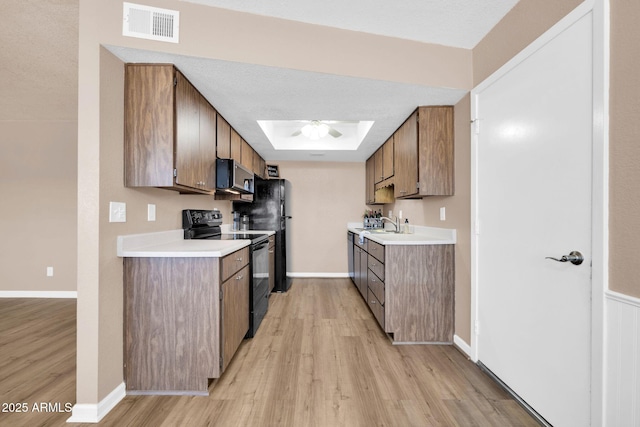 9639 W Cinnabar Ave Unit A, Peoria, AZ 85345 - kitchen featuring black range with electric stovetop, a skylight, light wood-style floors, light countertops, and stainless steel microwave
