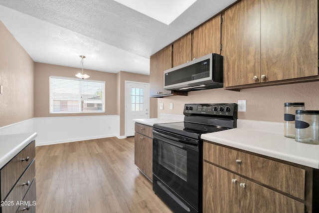 9639 W Cinnabar Ave Unit A, Peoria, AZ 85345 - kitchen with stainless steel microwave, black electric range, light wood-style flooring, light countertops, and a textured ceiling
