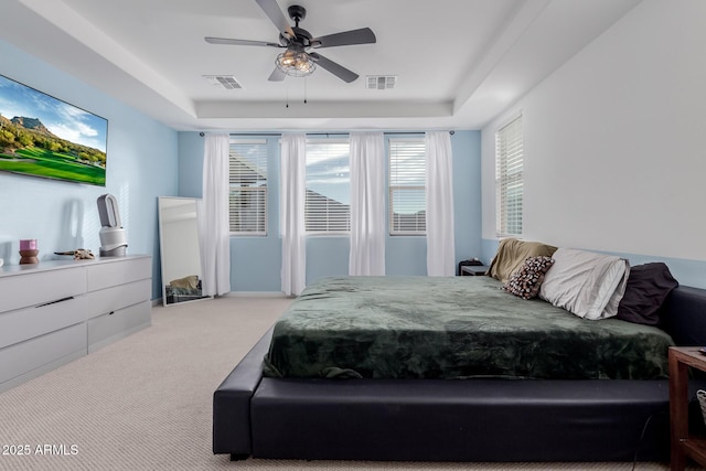 carpeted bedroom with ceiling fan and a raised ceiling