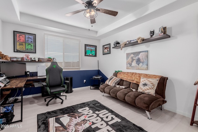 office area with a raised ceiling, ceiling fan, and light hardwood / wood-style flooring