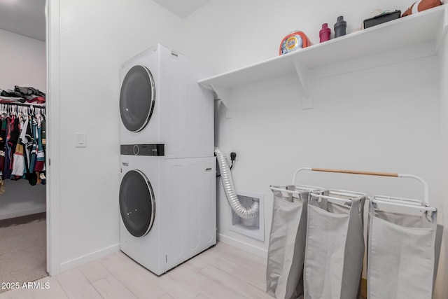 washroom with stacked washer and dryer and light hardwood / wood-style floors