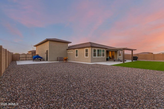 back house at dusk featuring a patio