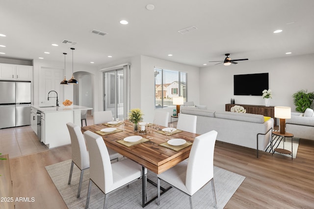 dining space with sink, light hardwood / wood-style flooring, and ceiling fan