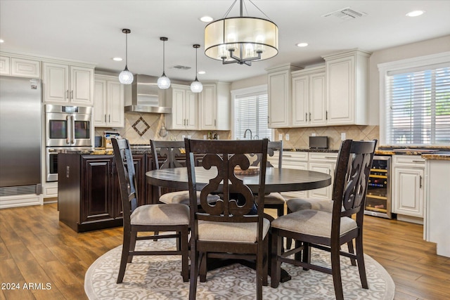 dining space featuring an inviting chandelier, beverage cooler, and dark hardwood / wood-style floors