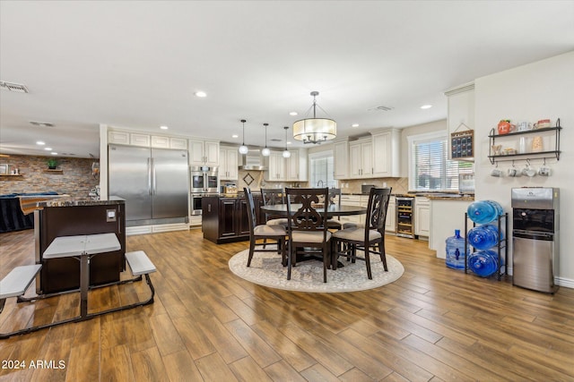 dining space featuring hardwood / wood-style floors, wine cooler, and an inviting chandelier