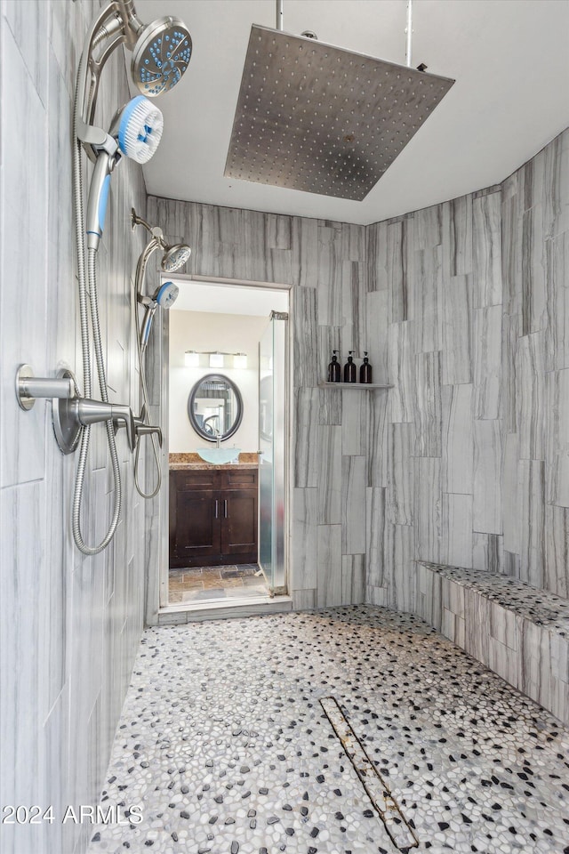 bathroom with vanity, tiled shower, and tile walls