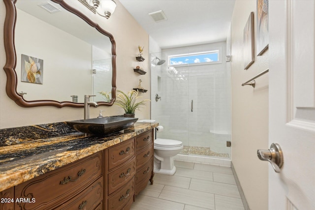 bathroom with tile patterned floors, vanity, a shower with door, and toilet