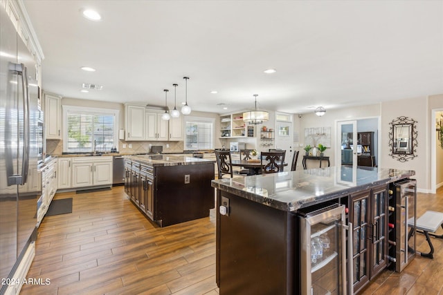 kitchen with wood-type flooring, pendant lighting, wine cooler, and a center island