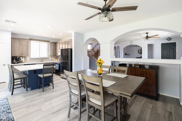 dining space featuring ceiling fan, sink, and light wood-type flooring