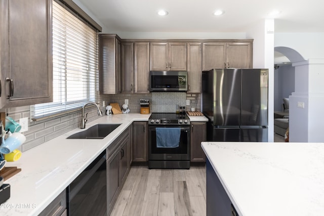 kitchen featuring stainless steel appliances, sink, decorative backsplash, and light hardwood / wood-style flooring