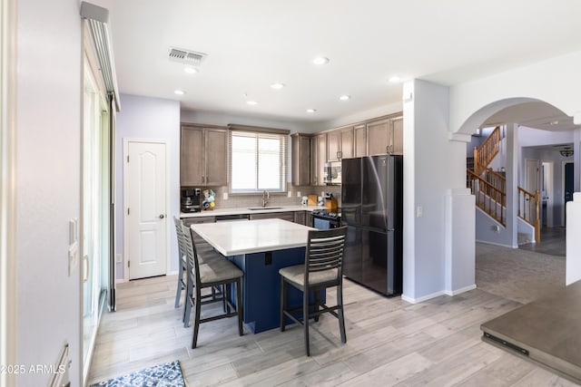 kitchen with sink, a breakfast bar area, a kitchen island, stainless steel appliances, and backsplash