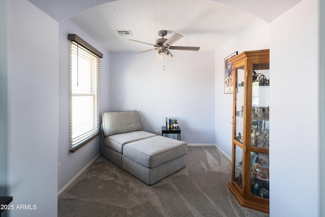 living area featuring ceiling fan and dark colored carpet